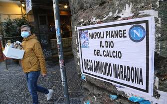 A man walks past a poster glued to a wall in downtown Naples reading "Napoli mourns the God of Football Diego Armando Maradona", a day after the death of Argentinian football legend Diego Maradona, on November 26, 2020 in Naples, southern Italy. - Maradona, widely remembered for his "Hand of God" goal against England in the 1986 World Cup quarter-finals, died on November 25, 2020 of a heart attack at his home near Buenos Aires in Argentina, while recovering from surgery to remove a blood clot on his brain. (Photo by Carlo Hermann / AFP) (Photo by CARLO HERMANN/AFP via Getty Images)