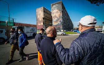 Napoli omaggia Maradona. Napoli's fans pay homage to Diego Armando Maradona near the huge mural by Italian artist Jorit Agoch depicting the Argentinian soccer legend, in the San Giovanni a Teduccio neighbourhood in Naples, Italy, 26 November 2020. Soccer legend Diego Maradona died on 25 November at the age of 60 after a heart attack. ANSA/ CESARE ABBATE