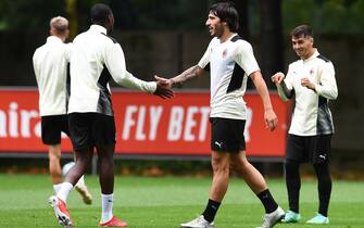 1330890806 CAIRATE, ITALY - JULY 27: Fode Ballo-Toure shakes hands with Sandro Tonali attends an AC Milan Training Session at Milanello on July 27, 2021 in Cairate, Italy. (Photo by Claudio Villa/AC Milan via Getty Images)