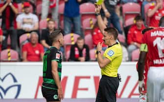 28 August 2021, Rhineland-Palatinate, Mainz: Football: Bundesliga, FSV Mainz 05 - SpVgg Greuther Fürth, Matchday 3, Mewa Arena. Referee Tobias Reichel (r) gives Fürth's Paul Seguin a yellow card. Photo: Sebastian Gollnow/dpa - IMPORTANT NOTE: In accordance with the regulations of the DFL Deutsche Fußball Liga and/or the DFB Deutscher Fußball-Bund, it is prohibited to use or have used photographs taken in the stadium and/or of the match in the form of sequence pictures and/or video-like photo series.
