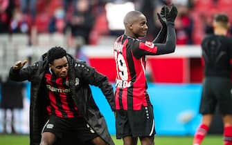 26 February 2022, North Rhine-Westphalia, Leverkusen: Soccer: Bundesliga, Bayer Leverkusen - Arminia Bielefeld, Matchday 24, BayArena. Leverkusen's Jeremie Frimpong (l) slaps Moussa Diaby on the butt after the match. Photo: Marius Becker/dpa - IMPORTANT NOTE: In accordance with the requirements of the DFL Deutsche Fußball Liga and the DFB Deutscher Fußball-Bund, it is prohibited to use or have used photographs taken in the stadium and/or of the match in the form of sequence pictures and/or video-like photo series.
