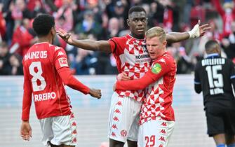 19 March 2022, Rhineland-Palatinate, Mainz: Soccer: Bundesliga, FSV Mainz 05 - Arminia Bielefeld, Matchday 27, Mewa Arena. Mainz's Moussa Niakhate (2nd from left) celebrates with his team after scoring a penalty to make it 2:0 and is lifted up by Jonathan Burkhardt. Photo: Torsten Silz/dpa - IMPORTANT NOTE: In accordance with the requirements of the DFL Deutsche Fußball Liga and the DFB Deutscher Fußball-Bund, it is prohibited to use or have used photographs taken in the stadium and/or of the match in the form of sequence pictures and/or video-like photo series.