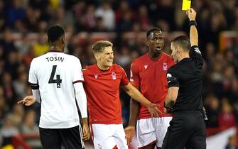 Referee Jarred Gillett (right) shows a yellow card to Nottingham Forest's Willy Boly (second right) during the Premier League match at The City Ground, Nottingham. Picture date: Friday September 16, 2022.