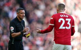 Referee Andre Marriner shows Manchester United's Luke Shaw a yellow card for unsporting behaviour during the Premier League match at Old Trafford, Manchester. Picture date: Saturday April 2, 2022.