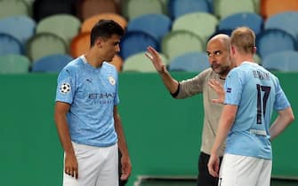 epa08606284 Headcoach Pep Guardiola of Manchester City (C) talks with his players Rodri (L) and Kevin De Bruyne (R) during the UEFA Champions League quarter final match between Manchester City and Olympique Lyon in Lisbon, Portugal 15 August 2020.  EPA/Miguel A. Lopes / POOL