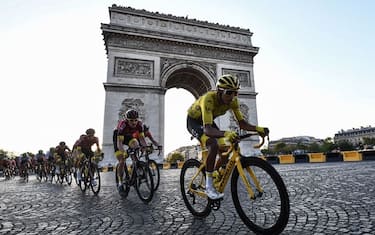 TOPSHOT - Colombia's Egan Bernal (R), wearing the overall leader's yellow jersey (C-R) and cyclists ride down the Champs Elysees avenue next to the Arc de Triomphe during the 21st and last stage of the 106th edition of the Tour de France cycling race between Rambouillet and Paris Champs-Elysees, in Paris, on July 28, 2019. (Photo by Anne-Christine POUJOULAT / AFP)        (Photo credit should read ANNE-CHRISTINE POUJOULAT/AFP via Getty Images)