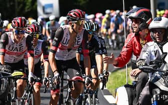 Race regulators speak with UAE Team Emirates team riders ahead of the pack of riders,  as the race is temporarily halted due to protest action on the race route during the 10th stage of the 109th edition of the Tour de France cycling race, 148,1 km between Morzine and Megeve, in the French Alps, on July 12, 2022. (Photo by Marco BERTORELLO / AFP) (Photo by MARCO BERTORELLO/AFP via Getty Images)