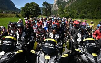 TOPSHOT - The pack of riders is temporarily immobilized by race regulators (front) due to protest action on the race route during the 10th stage of the 109th edition of the Tour de France cycling race, 148,1 km between Morzine and Megeve, in the French Alps, on July 12, 2022. (Photo by Marco BERTORELLO / AFP) (Photo by MARCO BERTORELLO/AFP via Getty Images)