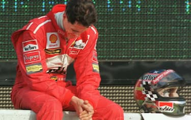 German F1 driver Michael Schumacher of Ferrari looks down in dejection after retiring from the race after the 32nd lap of the Formula One Japanese Grand Prix in Suzuka 01 November. Competing four-points behind leader and eventual winner Mika Hakkinen of Finland, Schumacher failed in his bid to win the driver's title. AFP PHOTO (Photo by TORU YAMANAKA / AFP) (Photo by TORU YAMANAKA/AFP via Getty Images)