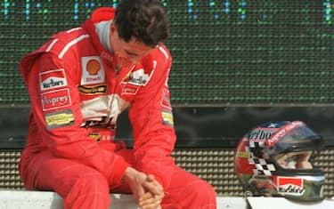 German F1 driver Michael Schumacher of Ferrari looks down in dejection after retiring from the race after the 32nd lap of the Formula One Japanese Grand Prix in Suzuka 01 November.  Competing four-points behind leader and eventual winner Mika Hakkinen of Finland, Schumacher failed in his bid to win the driver's title.  AFP PHOTO (Photo by TORU YAMANAKA / AFP) (Photo by TORU YAMANAKA/AFP via Getty Images)