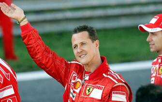 Monza, ITALY:  German Ferrari driver Michael Schumacher (L) waves to fans next to test-driver Luca Badoer during the Ferrari exhibition at the F1 race track in Monza 29 October 2006. The 37-year-old Schumacher, who retired as a driver after piloting his Ferrari to fourth place in the Brazilian Grand Prix last Sunday, is to stay with Ferrari as assistant to new chief executive officer Jean Todt.    AFP PHOTO / VINCENZO PINTO  (Photo credit should read VINCENZO PINTO/AFP via Getty Images)