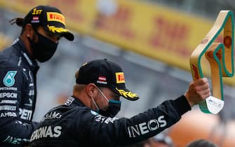 Mercedes' Finnish driver Valtteri Bottas (R) celebrates on the podium with the trophy next to Mercedes' British driver Lewis Hamilton after taking the 2nd place in the Formula One Styrian Grand Prix race on July 12, 2020 in Spielberg, Austria. (Photo by LEONHARD FOEGER / POOL / AFP) / ALTERNATIVE CROP (Photo by LEONHARD FOEGER/POOL/AFP via Getty Images)