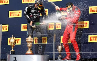 Mercedes' British driver Lewis Hamilton (L) and third placed Ferrari's Monegasque driver Charles Leclerc (R) spray the champagne on the winners' podium after winning the Formula One British Grand Prix at the Silverstone motor racing circuit in Silverstone, central England on August 2, 2020. - Lewis Hamilton survived a dramatic finale to win the British Grand Prix on Sunday, just making it across the line on three tyres to beat a fast closing Max Verstappen on Red Bull. The defending world champion claimed his seventh British Grand Prix win as Ferarri's Charles Leclerc came third and Daniel Ricciardo of Renault fourth. (Photo by ANDREW BOYERS / POOL / AFP) (Photo by ANDREW BOYERS/POOL/AFP via Getty Images)