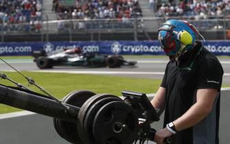 AUTODROMO HERMANOS RODRIGUEZ, MEXICO - NOVEMBER 05: A camera operator at work in a Luchador mask as Sir Lewis Hamilton, Mercedes W12, passes during the Mexican GP at Autodromo Hermanos Rodriguez on Friday November 05, 2021 in Mexico City, Mexico. (Photo by Charles Coates / LAT Images)