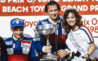 STREETS OF LONG BEACH, UNITED STATES OF AMERICA - MARCH 27: John Watson, 1st position, Niki Lauda, 2nd position, and RenÃ© Arnoux, 3rd position, celebrate on the podium with a glamour girl during the USA-West GP at Streets of Long Beach on March 27, 1983 in Streets of Long Beach, United States of America. (Photo by LAT Images)