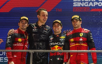 MARINA BAY STREET CIRCUIT, SINGAPORE - OCTOBER 02: Charles Leclerc, Ferrari, 2nd position, the Red Bull trophy delegate, Sergio Perez, Red Bull Racing, 1st position, and Carlos Sainz, Ferrari, 3rd position, on the podium during the Singapore GP at Marina Bay Street Circuit on Sunday October 02, 2022 in Singapore, Singapore. (Photo by Steven Tee / LAT Images)