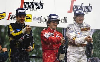 IMOLA, ITALY - MAY 05: Alain Prost, 1st position but later disqualified, celebrates on the podium alongside Elio de Angelis, 1st position, and Thierry Boutsen, 2nd position during the San Marino GP at Imola on May 05, 1985 in Imola, Italy. (Photo by Ercole Colombo / Studio Colombo)