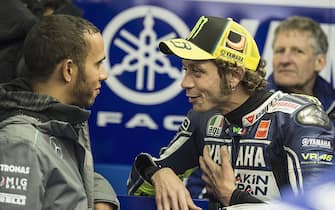 LE MANS, FRANCE - MAY 19:  Formula 1 driver Lewis Hamilton of Great Britain (L) speaks with Valentino Rossi of Italy and Yamaha Factory Racing before the MotoGP race during the MotoGP of France on May 19, 2013 in Le Mans, France.  (Photo by Mirco Lazzari gp/Getty Images)