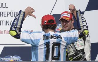 Italy's biker Valentino Rossi of Yamaha wears a jersey of the Argentine football team with the name of former star Diego Maradona on it, as he celebrates on the podium after winning the Argentina Grand Prix at Termas de Rio Hondo circuit, in Santiago del Estero, on April 19, 2015. Valentino Rossi survived a late battle with defending world champion Marc Marquez, who crashed with two laps to go.  AFP PHOTO / JUAN MABROMATA        (Photo credit should read JUAN MABROMATA/AFP via Getty Images)