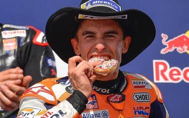 Marquez esulta mangiando una ciambella sul podio