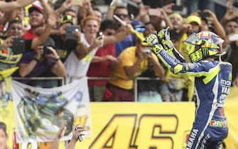 epa05242916 Italian MotoGP rider Valentino Rossi (R), of Yamaha, celebrates in front of fans after winning the second place during the Argentinian Motorcycle Grand Prix, at the Termas de Rio Hondo racetrack in Argentina, 03 April 2016.  EPA/DAVID FERNANDEZ