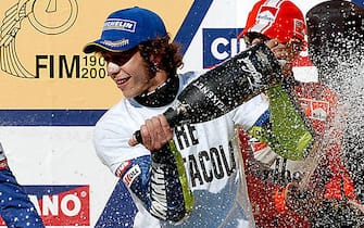 PHILLIP ISLAND, AUSTRALIA:  Reigning triple MotoGP World Champion Valentino Rossi soaks one of the podium girls with champagne as he celebrates with third place getter and compatriot Loris Capirossi (R) after his victory in the Australian MotoGP Grand Prix, Phillip Island, 17 October 2004. Rossi won a tight race with Sete Gibernau of Spain to capture his fourth consecutive World Title. AFP PHOTO/Paul CROCK  (Photo credit should read PAUL CROCK/AFP via Getty Images)