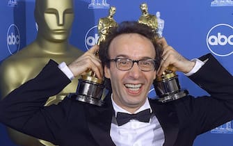 LOS ANGELES, UNITED STATES:  Roberto Benigni of Italy who won Oscars for Best Foreign Film and Best Actor in "Life Is Beautiful"  poses for photographers 21 March 1999 at the Dorothy Chandler Pavilion in Los Angeles during the 71st Annual Academy Awards.   (ELECTRONIC IMAGE)    AFP PHOTO/Hector MATA (Photo credit should read HECTOR MATA/AFP via Getty Images)