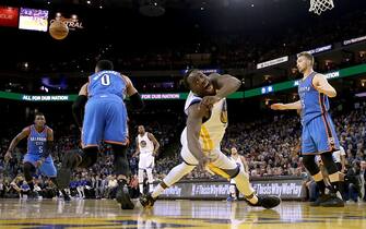 OAKLAND, CA - JANUARY 18:  Draymond Green #23 of the Golden State Warriors falls to the ground after loosing control of the ball while being guarded by Russell Westbrook #0 and Domantas Sabonis #3 of the Oklahoma City Thunder at ORACLE Arena on January 18, 2017 in Oakland, California.  NOTE TO USER: User expressly acknowledges and agrees that, by downloading and or using this photograph, User is consenting to the terms and conditions of the Getty Images License Agreement.  (Photo by Ezra Shaw/Getty Images)