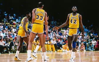LOS ANGELES, CA - 1985:  James Worthy #42, Kareem Abdul-Jabbar #33 and Magic Johnson #32 of the Los Angeles Lakers look on during a game circa 1988 at The Forum in Los Angeles, California. NOTE TO USER: User expressly acknowledges and agrees that, by downloading and/or using this Photograph, user is consenting to the terms and conditions of the Getty Images License Agreement. Mandatory Copyright Notice: Copyright 1988 NBAE (Photo by Andrew D. Bernstein/NBAE via Getty Images)