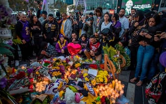People gather around a makeshift memorial for former NBA and Los Angeles Lakers player Kobe Bryant after learning of his death, at LA Live plaza in front of Staples Center in Los Angeles on January 26, 2020. - Nine people were killed in the helicopter crash which claimed the life of NBA star Kobe Bryant and his 13 year old daughter, Los Angeles officials confirmed on Sunday. Los Angeles County Sheriff Alex Villanueva said eight passengers and the pilot of the aircraft died in the accident. The helicopter crashed in foggy weather in the Los Angeles suburb of Calabasas. Authorities said firefighters received a call shortly at 9:47 am about the crash, which caused a brush fire on a hillside. (Photo by Apu GOMES / AFP) (Photo by APU GOMES/AFP via Getty Images)