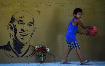 A boy with a basketball walks past a memorial wall for former Los Angeles Lakers basketball player Kobe Bryant following his death overnight in the US, near the "House of Kobe" gym built in honour of his 2016 visit to the Philippines, in Manila on January 27, 2020. (Photo by Maria TAN / AFP) (Photo by MARIA TAN/AFP via Getty Images)