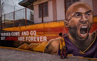 VALENZUELA, PHILIPPINES - JANUARY 28: A child stands next to a mural of former NBA star Kobe Bryant outside the "House of Kobe" basketball court on January 28, 2020 in Valenzuela, Metro Manila, Philippines. Bryant, who is hugely popular in basketball-obsessed Philippines, perished in a helicopter crash on January 26, 2020 in Calabasas, California. He died together with his 13-year-old daughter Gianna and seven others. (Photo by Ezra Acayan/Getty Images)