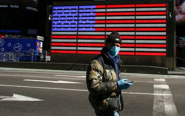 A man wears a face mask as he check his phone in Times Square on March 22, 2020 in New York City. - Coronavirus deaths soared across the United States and Europe on despite heightened restrictions as hospitals scrambled to find ventilators. (Photo by Kena Betancur / AFP) (Photo by KENA BETANCUR/AFP via Getty Images)