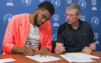 MINNEAPOLIS, MN - SEPTEMBER 23: Karl-Anthony Towns #32 of the Minnesota Timberwolves signs his contract extension with General Manager Scott Layden and Head Coach Tom Thibodeau on September 23, 2018 at the Minnesota Timberwolves and Lynx Courts at Mayo Clinic Square in Minneapolis, Minnesota. NOTE TO USER:  User expressly acknowledges and agrees that, by downloading and or using this Photograph, user is consenting to the terms and conditions of the Getty Images License Agreement. Mandatory Copyright Notice: Copyright 2018 NBAE (Photo by David Sherman/NBAE via Getty Images)