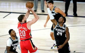 New Orleans Pelicans' Nicolo Melli (20) goes up for a shot against Sacramento Kings' Buddy Hield (24) and Kent Bazemore (26) during the first half of an NBA basketball game Thursday, Aug. 6, 2020 in Lake Buena Vista, Fla. (AP Photo/Ashley Landis, Pool)