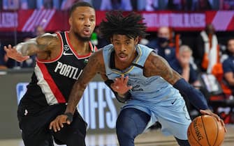 ORLANDO, FL - AUGUST 15: Ja Morant #12 of the Memphis Grizzlies drives to the basket around Damian Lillard #0 of the Portland Trail Blazers during the Western Conference Play in Game on August 15, 2020 in Orlando, Florida at The Field House at ESPN Wide World of Sports. NOTE TO USER: User expressly acknowledges and agrees that, by downloading and/or using this photograph, user is consenting to the terms and conditions of the Getty Images License Agreement.  Mandatory Copyright Notice: Copyright 2020 NBAE (Photo by Jesse D. Garrabrant/NBAE via Getty Images)