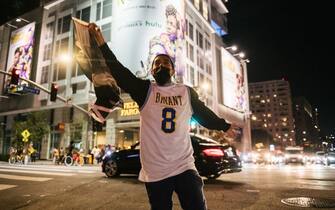 LOS ANGELES, CA - OCTOBER 11: A Lakers fan runs with a flag near the Staples Center on October 11, 2020 in Los Angeles, California. People gathered to celebrate after the Los Angeles Lakers defeated the Miami Heat in Game 6 of the NBA Finals. (Photo by Brandon Bell/Getty Images)