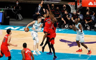 CHARLOTTE, NORTH CAROLINA - DECEMBER 12: LaMelo Ball #2 of the Charlotte Hornets looks to pass against DeAndre' Bembry #95 and Chris Boucher #25 of the Toronto Raptors during the second half of their game at Spectrum Center on December 12, 2020 in Charlotte, North Carolina. (Photo by Jared C. Tilton/Getty Images)