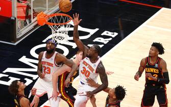 ATLANTA, GEORGIA - JANUARY 04:  Julius Randle #30 of the New York Knicks tips in this basket against Trae Young #11 and De'Andre Hunter #12 of the Atlanta Hawks during the second half at State Farm Arena on January 04, 2021 in Atlanta, Georgia.  NOTE TO USER: User expressly acknowledges and agrees that, by downloading and or using this photograph, User is consenting to the terms and conditions of the Getty Images License Agreement.  (Photo by Kevin C. Cox/Getty Images)