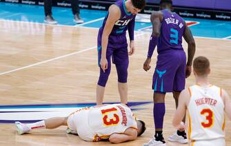 CHARLOTTE, NORTH CAROLINA - JANUARY 09: Bogdan Bogdanovic #13 of the Atlanta Hawks goes to the floor with an injury as LaMelo Ball #2 and Terry Rozier #3 of the Charlotte Hornets look on during the second quarter of their game at Spectrum Center on January 09, 2021 in Charlotte, North Carolina. NOTE TO USER: User expressly acknowledges and agrees that, by downloading and or using this photograph, User is consenting to the terms and conditions of the Getty Images License Agreement. (Photo by Jared C. Tilton/Getty Images)