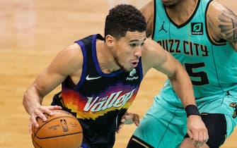 1309615913 CHARLOTTE, NORTH CAROLINA - MARCH 28: Devin Booker #1 of the Phoenix Suns drives to the basket while guarded by P.J. Washington #25 of the Charlotte Hornets during the third quarter during their game at Spectrum Center on March 28, 2021 in Charlotte, North Carolina. NOTE TO USER: User expressly acknowledges and agrees that, by downloading and or using this photograph, User is consenting to the terms and conditions of the Getty Images License Agreement. (Photo by Jacob Kupferman/Getty Images)