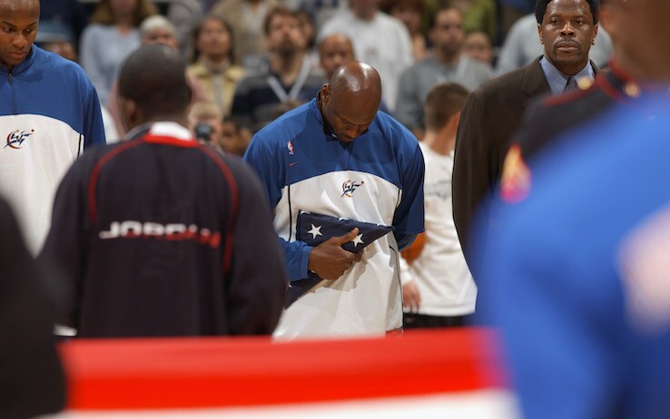 1955825 WASHINGTON - APRIL 14: Michael Jordan #23 of the Washington Wizards listens to the National Anthem as he holds a flag that was presented to him by U.S. Secretary of Defense Donald Rumsfeld, the flag flew over the Pentagon on September 11, 2001, during pregame ceremonies on Michael Jordan's final home game, as the Washington Wizards host the New York Knicks at MCI Center on April 14, 2003 in Washington, DC. The Knicks won 93-79. NOTE TO USER: User expressly acknowledges and agrees that by downloading and/ or using this photograph, user is consenting to the terms and conditions of the Getty Images license agreement. (Photo by Doug Pensinger/Getty Images)