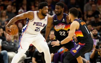PHOENIX, ARIZONA - MARCH 27: Joel Embiid #21 of the Philadelphia 76ers handles the ball against Deandre Ayton #22 and Devin Booker #1 of the Phoenix Suns during the second half of the NBA game at Footprint Center on March 27, 2022 in Phoenix, Arizona. The Suns defeated the 76ers 114-104.  NOTE TO USER: User expressly acknowledges and agrees that, by downloading and or using this photograph, User is consenting to the terms and conditions of the Getty Images License Agreement. (Photo by Christian Petersen/Getty Images)