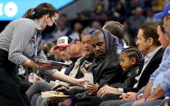 SAN FRANCISCO, CALIFORNIA -  MARCH 16: A food server delivers beverages to Kanye West, center, and his son, Saint West, as they watch the game with Golden State Warriors co-owners Joe Lacob and Peter Guber against the Boston Celtics in the second quarter at Chase Center in San Francisco, Calif., on Wednesday, March 16, 2022.  (Photo by Ray Chavez/MediaNews Group/The Mercury News via Getty Images)