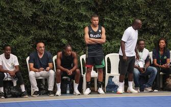 Paris Saint-Germain and France national football team star striker Kylian Mbappe (C) looks on from the touchline after playing basketball with former professional basketball player Joakim Noah (not seen) at the Club Noah sports complex in Yaounde on July 7, 2023. (Photo by Daniel BELOUMOU OLOMO / AFP) (Photo by DANIEL BELOUMOU OLOMO/AFP via Getty Images)