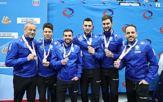 epa09607852 Italy's coaches Claudio Pescia and Mattia Giovanella with players Sebastiano Arman, Simone Gonin, Amos Mosaner, and Joel Retornaz pose with their bronze medals on the podium of the 2021 European Curling Championships at the Olympic Park in Lillehammer, Norway, 27 November 2021.  EPA/Geir Olsen  NORWAY OUT