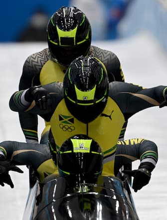 19 February 2022, China, Yanqing: Bobsleigh, Olympics, four-man bobsleigh, men, heat 2, at the National Sliding Centre, Jamaica's Shanwayne Stephens (front) takes off with his teammates. Photo: Robert Michael/dpa-Zentralbild/dpa