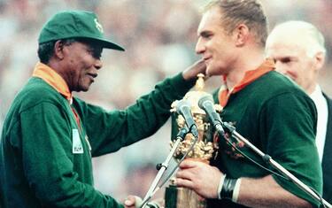 Picture taken on June 24, 1995 at Johannesburg showing South African President Nelson Mandela (L) congratulating Springbok skipper François Pienaar after handing him the William Webb Ellis trophy. - The Springboks beat New Zealand 15-12 after over-time in the rugby World Cup final. (Photo by Jean-Pierre MULLER / AFP)        (Photo credit should read JEAN-PIERRE MULLER/AFP via Getty Images)