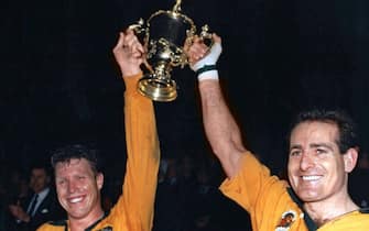 Australian captain Nick Farr-Jones (L) and team-mate David Campese raise the Webb Ellis Cup after the 1991 Rugby World Cup final match Australia vs England at Twickenham on November 02, 1991. AFP PHOTO (Photo by - / AFP) (Photo by -/AFP via Getty Images)