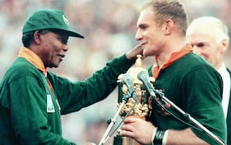 Picture taken on June 24, 1995 at Johannesburg showing South African President Nelson Mandela (L) congratulating Springbok skipper François Pienaar after handing him the William Webb Ellis trophy. - The Springboks beat New Zealand 15-12 after over-time in the rugby World Cup final. (Photo by Jean-Pierre MULLER / AFP)        (Photo credit should read JEAN-PIERRE MULLER/AFP via Getty Images)